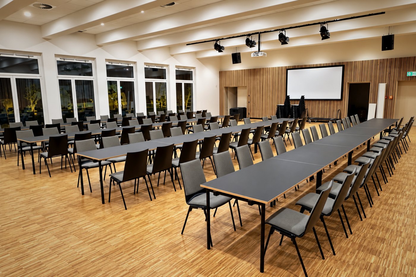Veranstaltungssaal mit Tischen in Reihenaufstellung