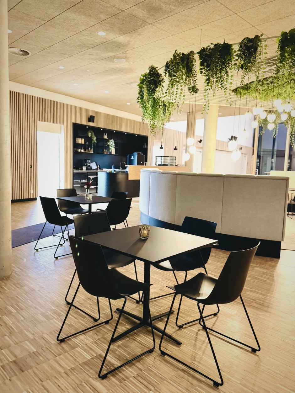 Café-Bereich mit Bistrotischen, Schalenstühlen und Sitzbank