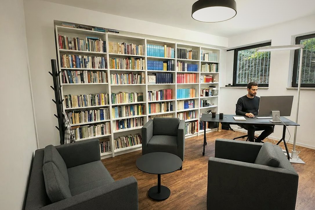 Bibliothek mit Besprechungssesseln und Arbeitsplatz